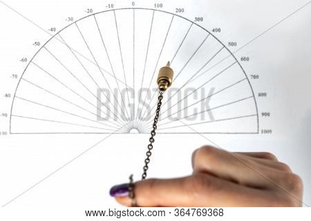 Arm Of A Dowser With Hand-held Pendulum Over The Chart. Selective Focus.