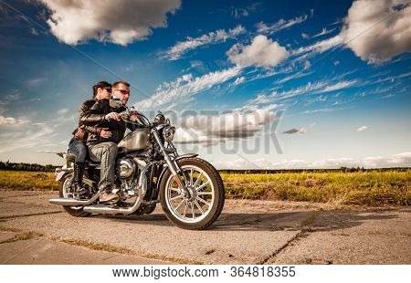 Couple Bikers in a leather jacket riding a motorcycle on the road
