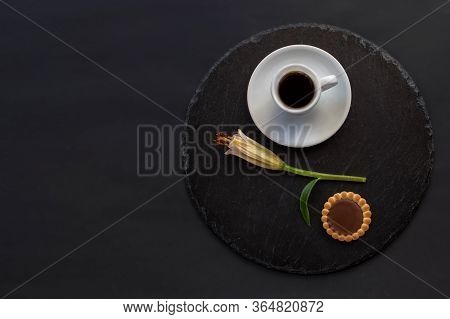 Cup Of Black Coffee Tea, Cookie With Chocolate, Single Bud Of Lily Flower On A Round Slate On A Blac