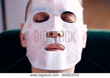 closeup of a handsome caucasian man wearing a bio-cellulose sheet mask at home