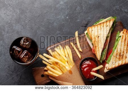Club sandwich, potato fries chips and glass of cola drink with ice. Fast food take away. Top view with copy space