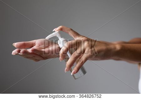 Close up view of woman person using small portable antibacterial hand sanitizer on hands. Stock photo