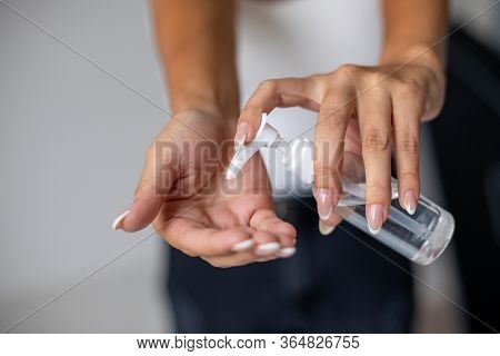 Close up view of woman person using small portable antibacterial hand sanitizer on hands. Stock photo