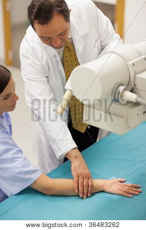 Medico ponendo il braccio del paziente su un tavolo in una stanza di radiografia