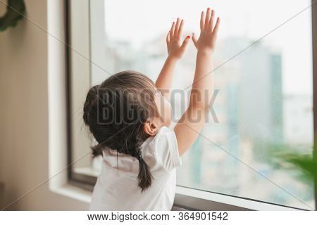 A Lovely Kid Girl Sitting And Looking Outside Trough The Window