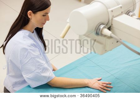 Paziente ponendo la sua mano su una tabella medica in una stanza di radiografia