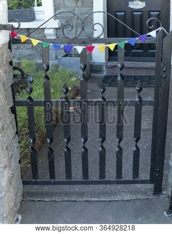 A Close Up View Of A Small Black Gate That Has Bright Coloured Ribben And Bunting