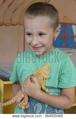 A Child With A Reptile. The Boy Holds A Lizard In His Hands.