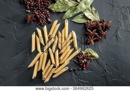 Raw Pasta Rests On A Table With Pepper Bay Leaf Badyan And Spicy Spices On A Dark Background
