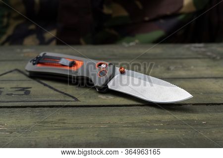 The Reverse Side Of The Knife. The Knife Is Tilted. Knife With An Orange Handle And A Clip For Carry