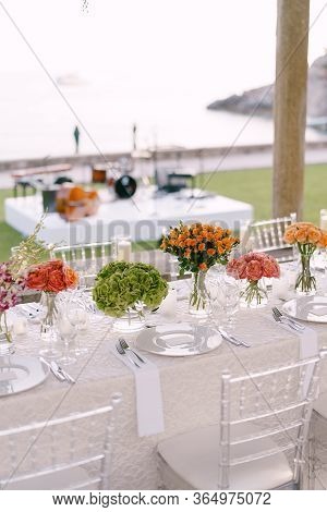 Wedding Dinner Table Reception. A Very Long Table For Guests With A White Tablecloth, Floral Arrange