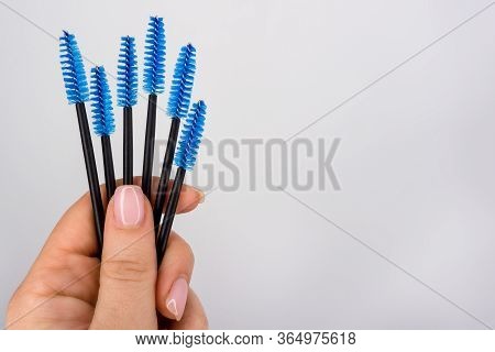 Set Of Eyelash Brushes In Hand On White Background. Copy Space For Text. Blue, Black Yelash Brush In