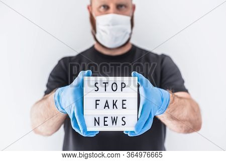 Fake News Infodemics During Covid-19 Pandemic Concept. Man Wearing Protective Mask And Medical Glove