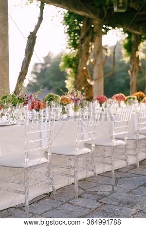 Wedding Dinner Table Reception. Clear Glass Chairs Chiavari, Tiffany, Stand Near Table With Flowers.