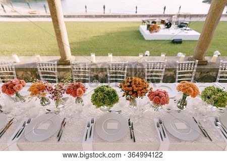 Wedding Dinner Table Reception. A Very Long Table For Guests With A White Tablecloth, Floral Arrange
