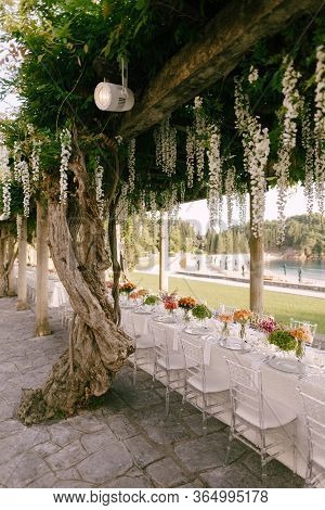 Wedding Dinner Table Reception. A Very Long Table For Guests With A White Tablecloth, Floral Arrange