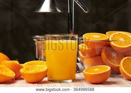 Squeezing an orange with a manual press, close view, making a glass of fresh. Fresh oranges on a wooden table, whole, squeezed and sliced.