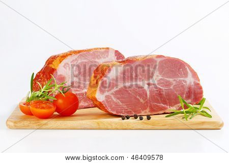 Seitenansicht der Geräuchertes Schweinefleisch Hals Blöcke mit Gemüse, auf ein hölzernes Schneidebrett