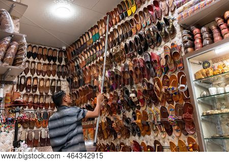 Jodhpur, Rajasthan, India - 20.10.2019 : Shop Owner Bringing Down Colorful Rajsathani Ladies Shoes A