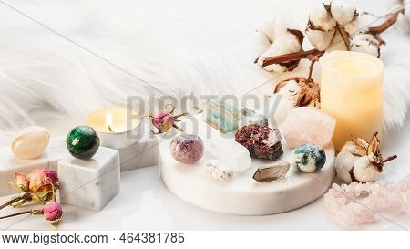 Minerals Collection On White Marble Stand With Burning Candles And Dry Flowers. Healing Stones For W