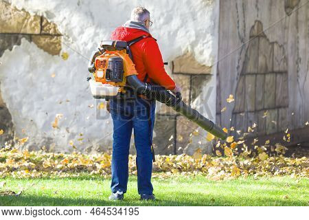 Leaf Blower Male Worker Removes Leaves Lawn Of Garden Autumn. Removing Fallen Leaves In Autumn. Park