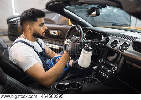 Professional Chemical Cleaning Of Interior Of Luxury Car By Air Gun. Male Bearded Worker Of Auto Ser