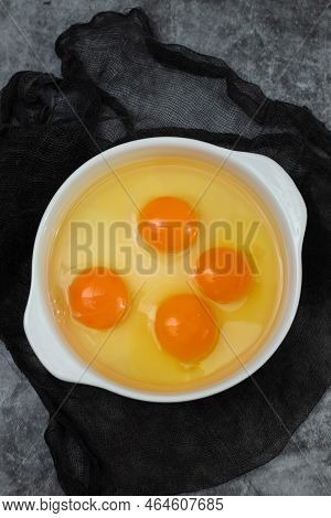 Few Yellow Egg Yolks In A White Bowl On Dark
