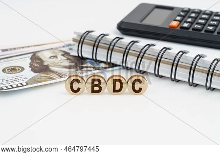 Business Concept. On A White Surface Are Dollars, A Notebook, A Calculator And Wooden Circles With T