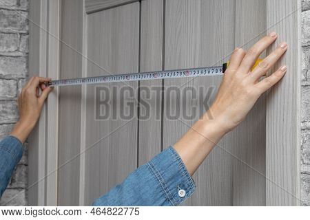 Man Measuring A Doorway With A Tape Measure. Woman Using A Tape Measure