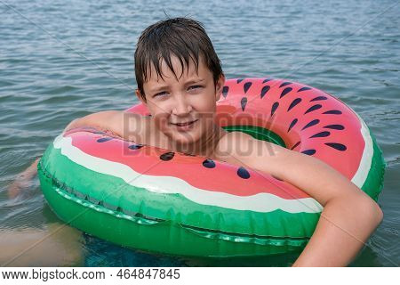 A Young Playful Happy Teenage Boy Relaxing On An Inflatable Ring , Floaty In The Sea During Summer V