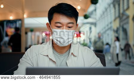 Smiling Man In Protective Mask Look At Laptop Screen Chatting Remote With Friend On Social Media Wat