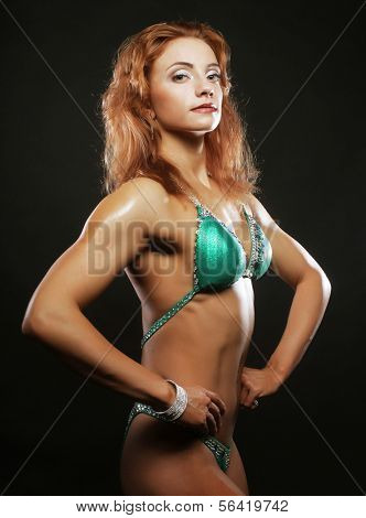 A beautiful woman bodybuilder posing in green  bikini