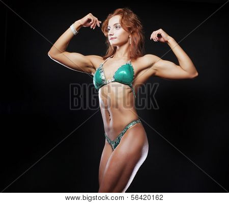 A beautiful woman bodybuilder posing in green  bikini
