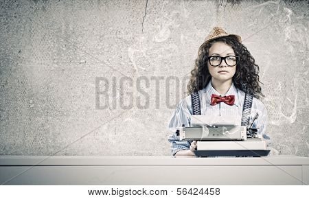 Young funny woman in glasses using typewriter