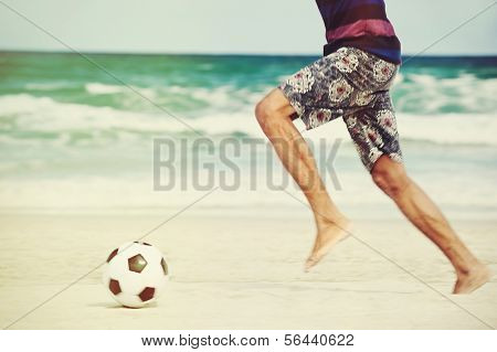 Hispanic Brasil man playing soccer on beach with dribble skill and ball on vacation