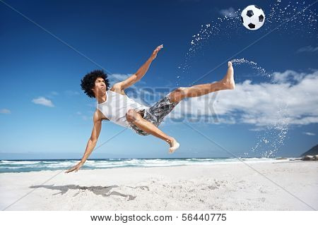 Latino Hispanic man doing bicycle kick on beach with soccer ball