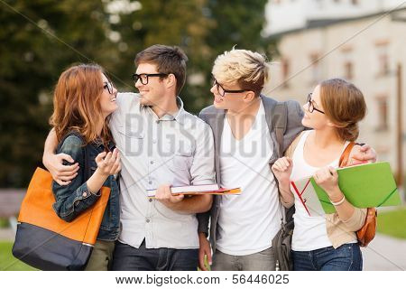 summer holidays, education, campus and teenage concept - group of students or teenagers with files, folders and eyeglasses hanging out