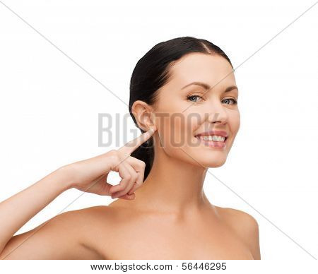 health, spa and beauty concept - clean face of beautiful young woman pointing to her ear