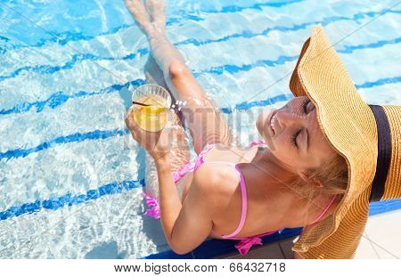 Woman In A Hat Enjoying Cocktail In A Swimming Pool
