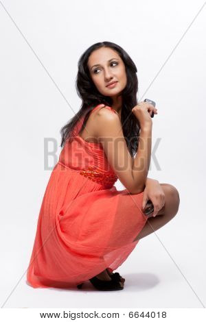 sognando la ragazza dai capelli scura in peachy bel vestito con il cellulare