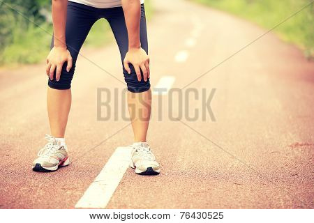 tired woman runner taking a rest after running hard in countryside road. sweaty athlete after marath