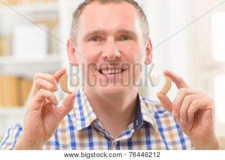 Man showing deaf aid in ear