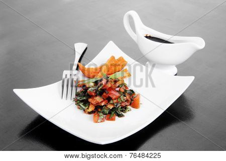 vegetable salad : cherry tomatoes and basil with sweet baked potato served on white plate with sauce boat full blask soy sauce on wood