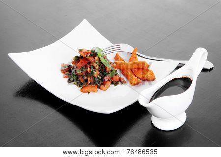 vegetable salad : cherry tomatoes and basil with sweet baked potato served on white plate with sauceboat full blask soy sauce on wood