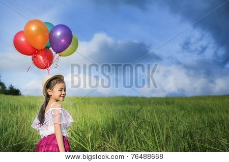 Young Asia Girl Holds Tightly To A Large Bunch Of Helium Filled Balloons