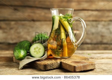 Glass ewer with fresh organic cucumber water on wooden table