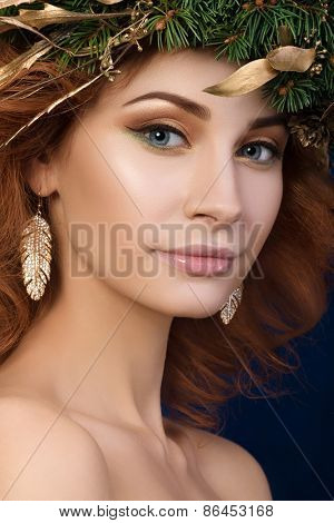 Portrait of young beautiful redhaired woman with firry wreath with golden leaves