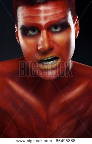 Portrait of a handsome young man in a red body painting
