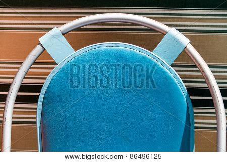 A blue coloured cushion on a metal curved frame with a background with coloured lines