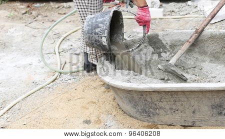 Constrution work put water on concrete mixing tray in building site